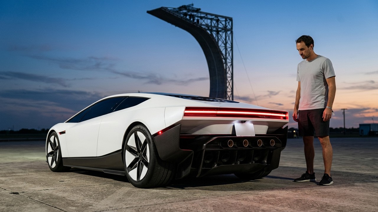 Gjeebs beside a white concept sports car at dusk